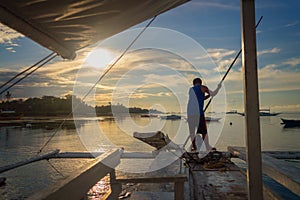 Fisherman on a banka, traditional filipino fishing boat at sunset, Cebu island The Philippines