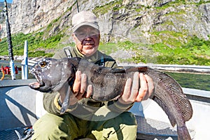 Fisherman with big wolffish near Lofoten, Senija, Alta Norway. Man holding catch Atlantic wolf fish