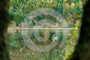 Fisherman in boat in automn day. fishing on lake inside the forest photo