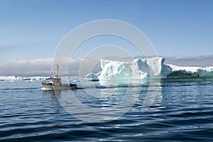 Fisherman boat between Icebergs, Disko Bay, Greenland photo