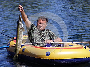 The fisherman in the boat with a pike