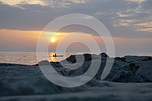 Fisherman in the boat at sea at sunset.