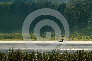 Fisherman on a boat silhouette with forest view