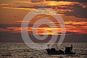 Fisherman in a boat at sunset