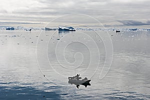 Fisherman boats between icebergs in Arcitic Ocean, Greenland