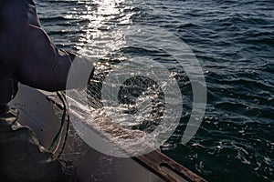 Fisherman bringing back net in a boat