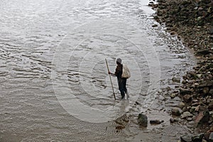 A fisherman carrying bag with a bamboo pole, will to the tidal flat