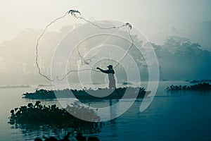 Fisherman casting out his fishing net in the river. photo
