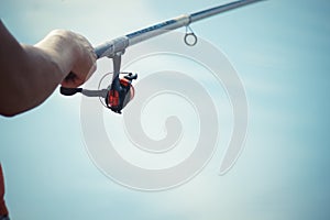 Fisherman catches a fish. Hands of a fisherman with a spinning rod in hand closeup. Spin fishing reel