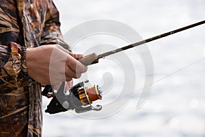 A fisherman catches a fish. Hands of a fisherman with a spinning rod in hand closeup