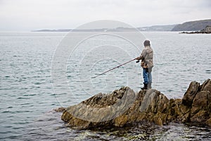 Fisherman catches fish on the rocks