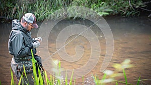 A fisherman catches spinning in the waders. Trout fishing photo