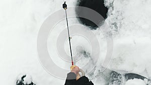 Fisherman catching fish in hole in ice on pond. Vertical video