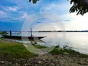 A Fisherman catching a fish with a net in a river. Photo captured at the afternoon time. His boat was parked at the river bank.