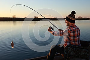 Fisherman catching fish with rod at riverside