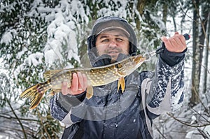 A fisherman caught a pike on winter fishing