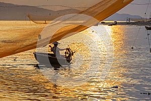 Fisherman checks his nets in early morning on river in Hoian, Vietnam