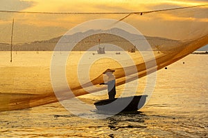 Fisherman checks his nets in early morning on river in Hoian, Vietnam