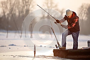 Fisherman draws out fish from cold water on winter