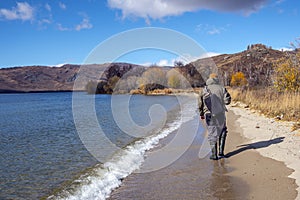 Fisherman with fiching rod on a lake in autumn.
