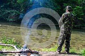 The fisherman fishes on a mountain river. Campfire nearby