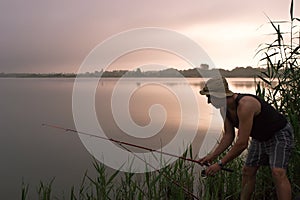 Fisherman fishing on the bank of the lake at sunrise