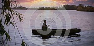 Fisherman fishing on bank of river at sunset