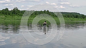 Fisherman fishing in a calm river in the morning. Man in fishing gear stending in a river