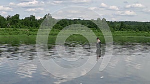 Fisherman fishing in a calm river in the morning. Man in fishing gear stending in a river