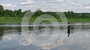 Fisherman fishing in a calm river in the morning. Man in fishing gear stending in a river