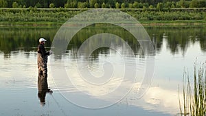 Fisherman fishing in a calm river in the morning. Man in fishing gear stending in a river