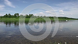 Fisherman fishing in a calm river in the morning. Man in fishing gear stending in a river and throws a fishing pole