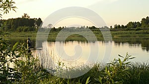 Fisherman fishing in a calm river in the morning. Man in fishing gear stending in a river and throws a fishing pole