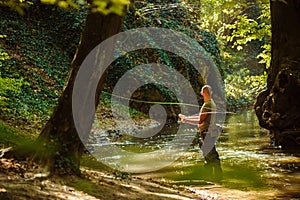 A fisherman fishing in the flowing stream