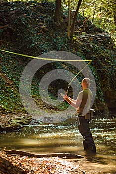 A fisherman fishing in the flowing stream