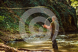 A fisherman fishing in the flowing stream