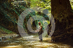 A fisherman fishing in the flowing stream