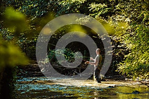 A fisherman fishing in the flowing stream