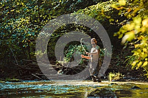 A fisherman fishing in the flowing stream