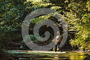 A fisherman fishing in the flowing stream