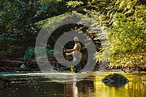 A fisherman fishing in the flowing stream