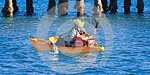 Fisherman with fishing gear paddling a Kayak.