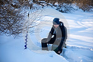 A fisherman fishing in a hole in the ice to catch fish, Tom river in Kemerovo, Russia