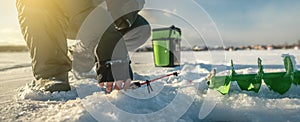 Fisherman is fishing in a hole on a large frozen lake on a sunny day. The joy of winter fishing