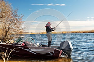 A fisherman is fishing on the river from a boat. Fisherman athlete. Male enthusiastic fishing in early spring