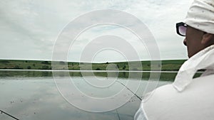 Fisherman fishing at river shore. Man catching fish on lake at beautiful nature. Male sitting with fishing rod near river shore. F