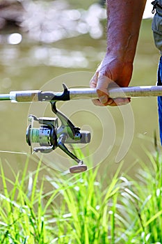 A fisherman with a fishing rod. Close-up of a hand holding spinning rod