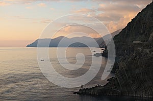 Fisherman with a fishing rod on the edge of the rock. Riomaggiore. Cinque Terre. Italy.