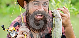 Fisherman with fishing rod in hand pulling fish caught from river. Man hold big fish trout in his hands. Fisherman and