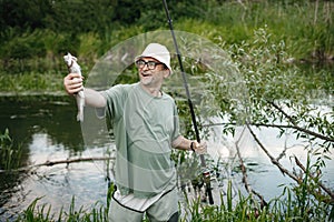 Fisherman with fishing rod near the lake at summer